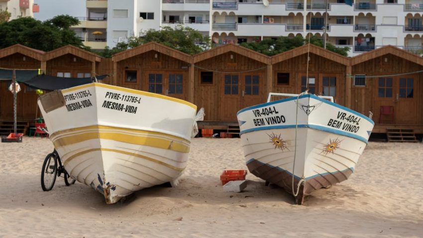 Colorful fishing boats resting on sandy Monte Gordo beach, Faro, Portugal.
